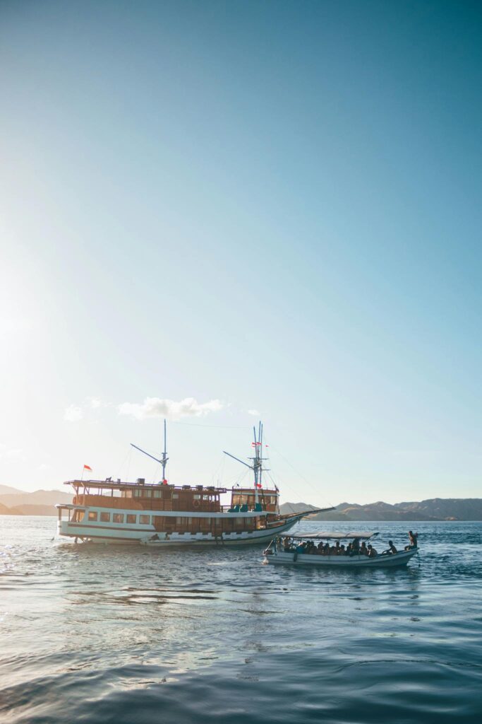 A traditional boat navigating the scenic waters of Komodo, Indonesia against a clear blue sky.